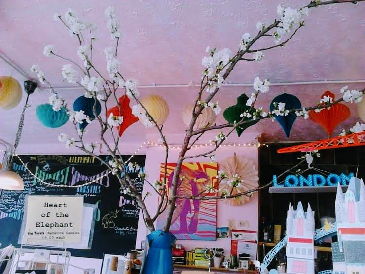 Pastel pink walls, large blackboard with coloured chalk menu, a large branch of blossom in a blue metal vase.
the Heart of the Elephant is typed on paper